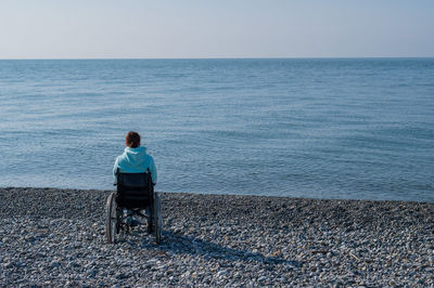 Rear view of man standing at beach against sky