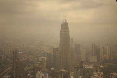 Aerial view of buildings in city against cloudy sky