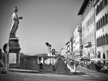 Statues on street amidst buildings in city against sky