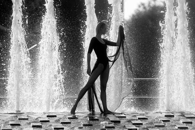 Full length of woman standing against water fountain