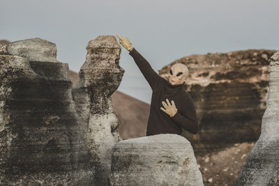 Front view of man wearing mask pointing at rock