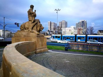 Statue in city against cloudy sky