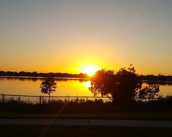 Silhouette trees by lake against sky during sunset