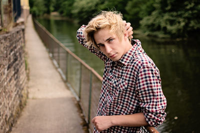 Portrait of handsome young man leaning on railing at footbridge