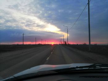 Road against sky seen through car windshield during sunset