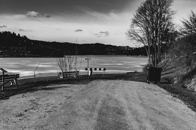 Empty road by lake against sky