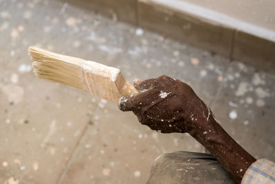 Cropped hand of worker holding paintbrush