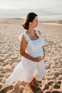 Young woman standing on beach against sea