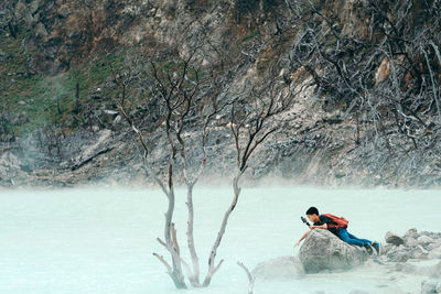 Side view of boy lying on rock in river