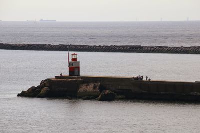 Lighthouse by sea against sky