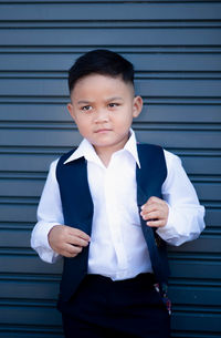 Portrait of boy standing against wall