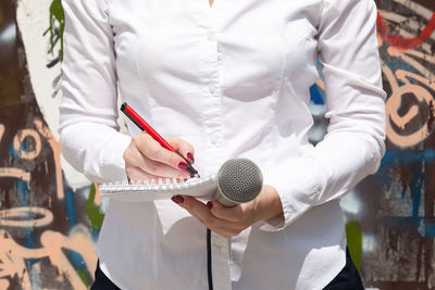 Midsection of journalist writing in books