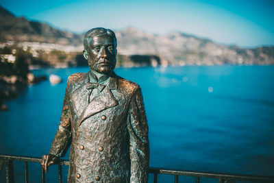 Close-up of statue by sea against sky