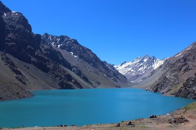 Scenic view of lake and mountains against clear blue sky