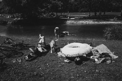 People sitting on field by lake