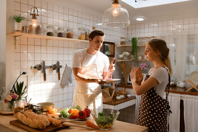 Young couple prepares cooking a breakfast in kitchen with a fun smile and happiness