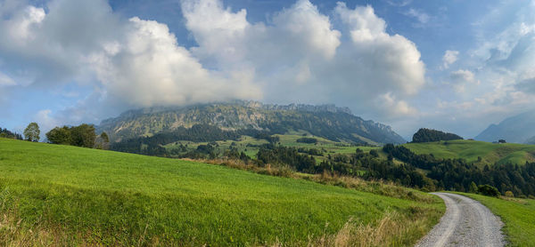 Panoramic view of road amidst field against sky