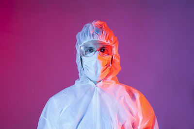 Portrait of man with chemical protective equipment for covid-19 against colored background