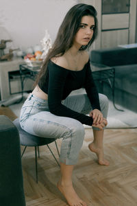 Young woman sitting on hardwood floor at home