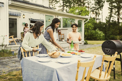 Siblings setting up food on table in back yard