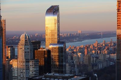 Modern buildings in city against sky during sunset