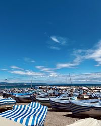 Boats moored at harbor against blue sky