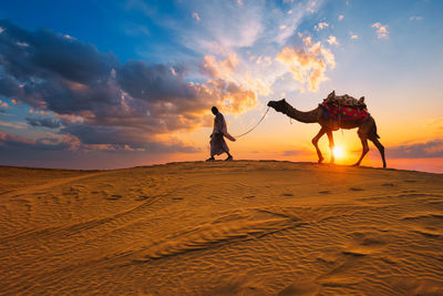 Rear view of man walking on sand at desert