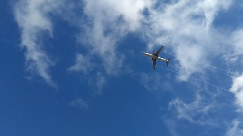 Low angle view of airplane flying against blue sky