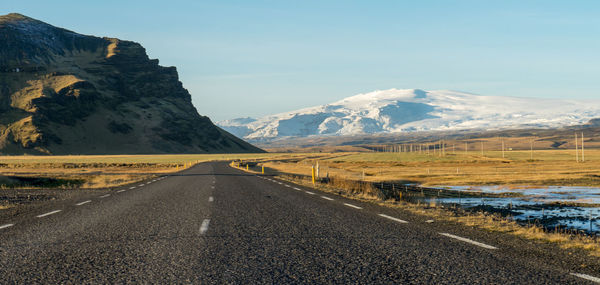 Road by mountains against sky