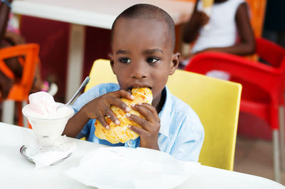 Portrait of boy eating ice cream in restaurant