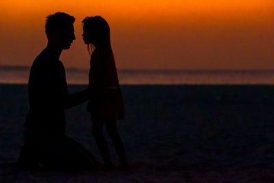 Silhouette couple standing on beach during sunset