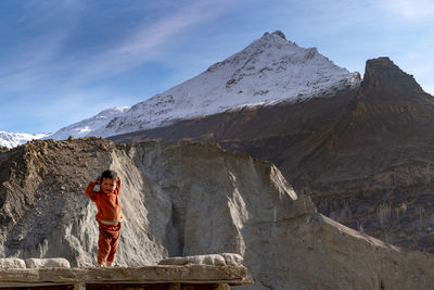 Woman standing on rock against mountains