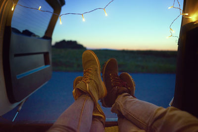 Low section of people relaxing against sky during sunset