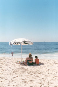 People on beach against clear sky