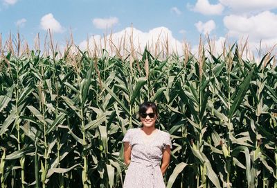 Portrait of smiling woman standing against plants on agricultural field