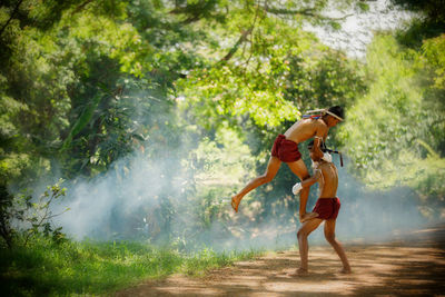 Full length of shirtless warriors fighting in forest