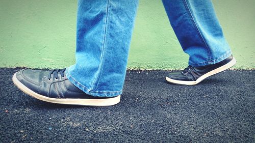 Low section of man standing against blue wall