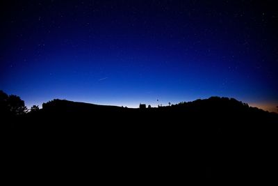 Low angle view of silhouette landscape against clear sky at night