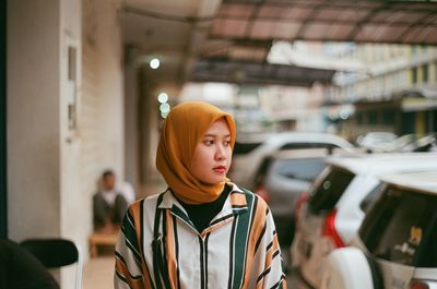 Portrait of young woman looking away while standing in bus