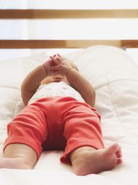 Midsection of girl lying on bed at home