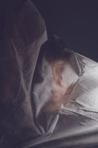 Woman face covered with textile against black background