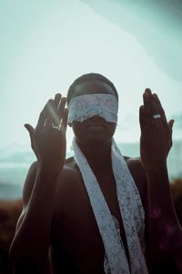 Man with blindfold gesturing while standing outdoors