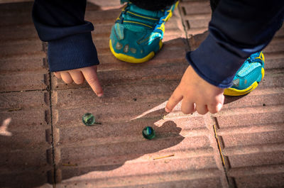 Low section of child playing with marbles on footpath