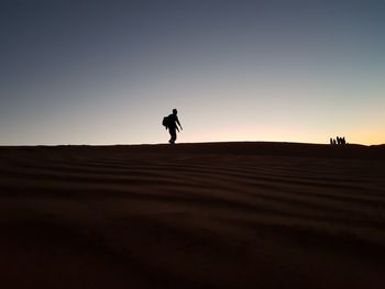 Silhouette man on desert against sky during sunset