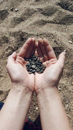 Cropped hands holding stones at beach