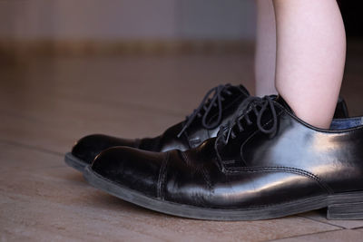 Low section of child wearing shoes on floor