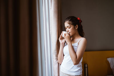 Portrait of young woman standing against wall