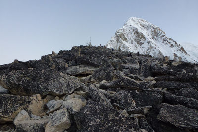 Low angle view of rocks on mountain against clear sky