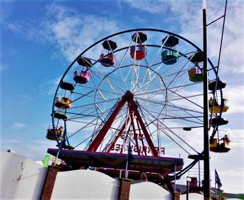 Low angle view of ferris wheel against cloudy sky