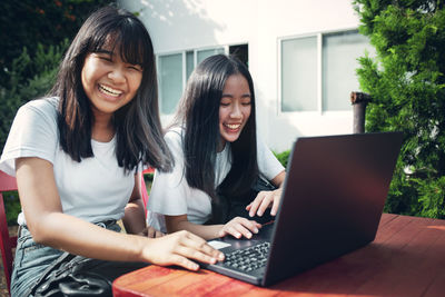 Young woman using mobile phone while sitting in laptop